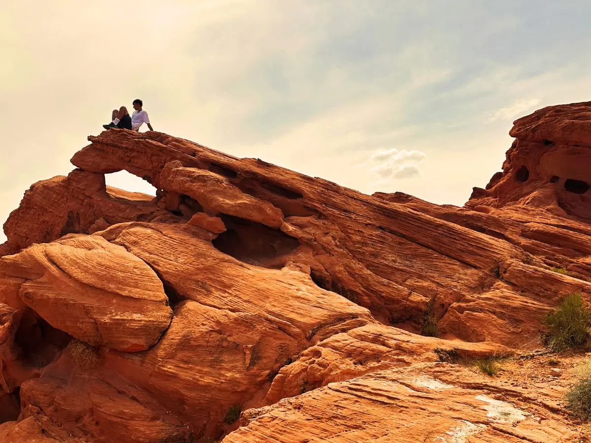 Adolescent assis en haut d'un rocher rouge et regardant au loin à Valley of Fire, Nevada.