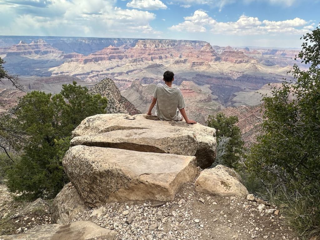 Adolescent assis sur un rocher, les jambes dans le vide, à Grandview Point au Grand Canyon