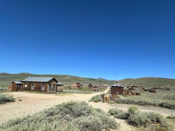 Photo du village de Bodie Ghost Town avec les maisons le long de la route sur fond de ciel bleu.