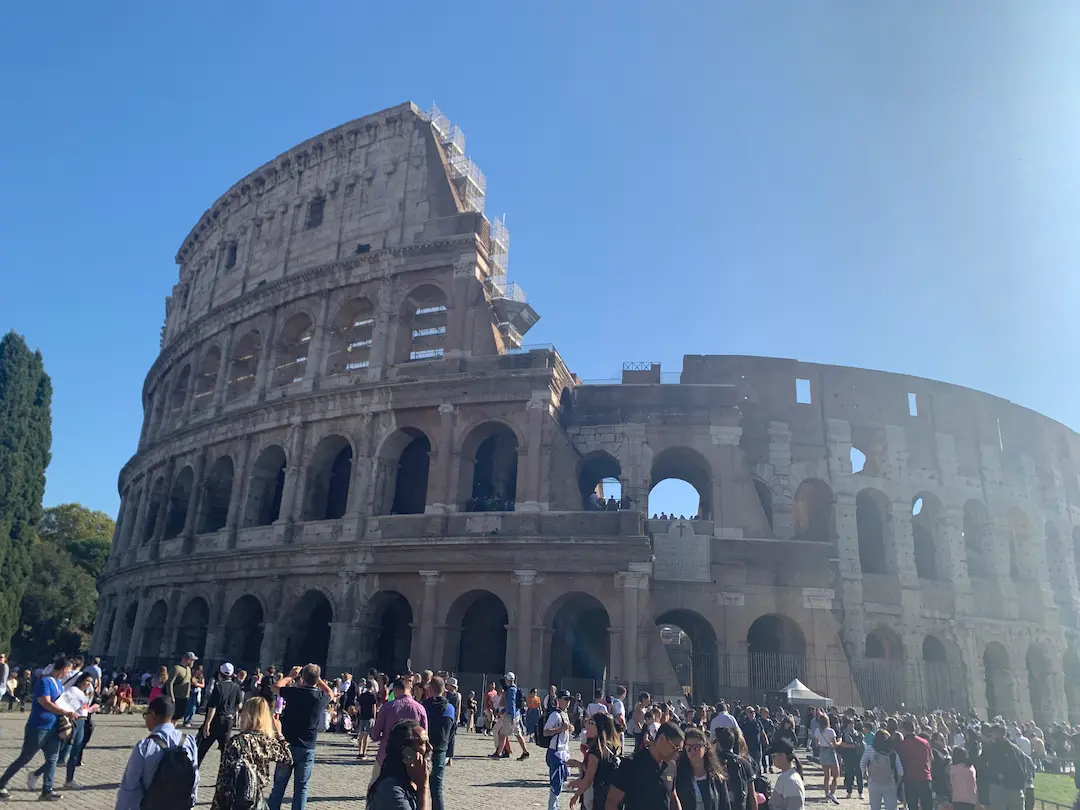 Photo du Colisée de Rome, sur fond de ciel bleu, avec la foule devant