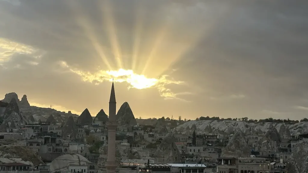 Coucher de soleil pris en photo depuis les hauteurs de Göreme, avec les rayons du soleil qui percent a travers les nuages au dessus du minaret, Cappadoce Turquie