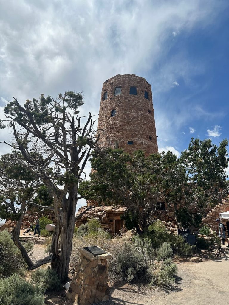 Photo de la tour Desert View Watchover au Grand Canyon avec un arbre au premier plan et le ciel bleu en fond