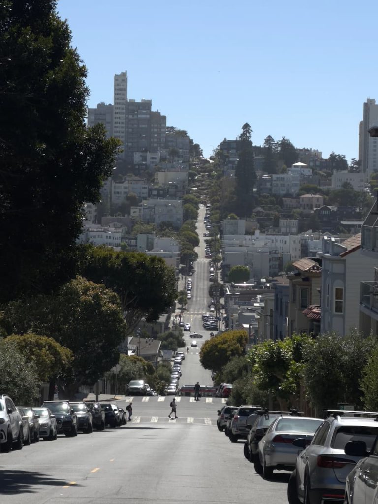 Vue de loin des rues en pente avec Lombard Street et ses lacets en fond à San Francisco Californie