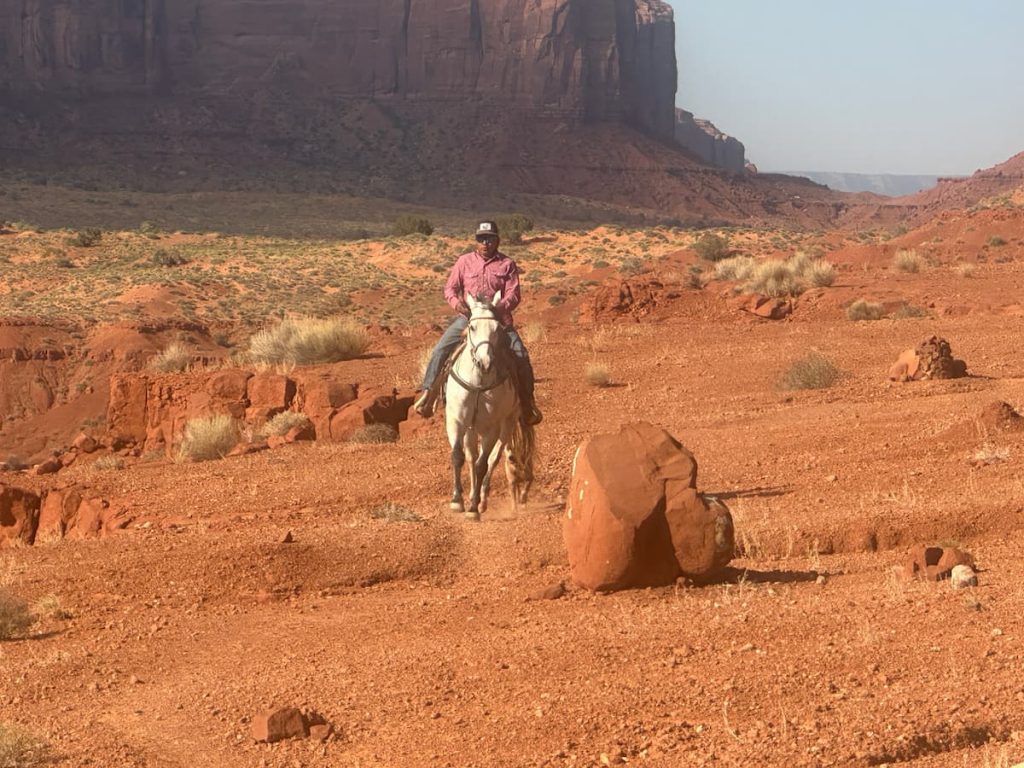 Indien Navajo sur un cheval blanc dans la vallée à Monument Valley los d'une visite guidée en famille