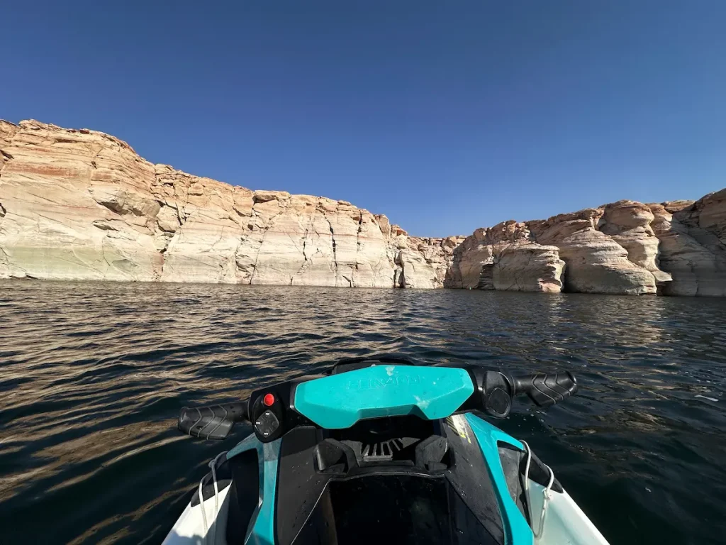 Photo de l'avant d'un jet ski prise par la personne qui conduit, sur le Lake Powell, avec les falaises blanche en fond et l'ouverture sur un canyon