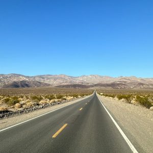 Photo d'une route goudronnée dans la Death Valley qui se perd au fond dans les montagnes.