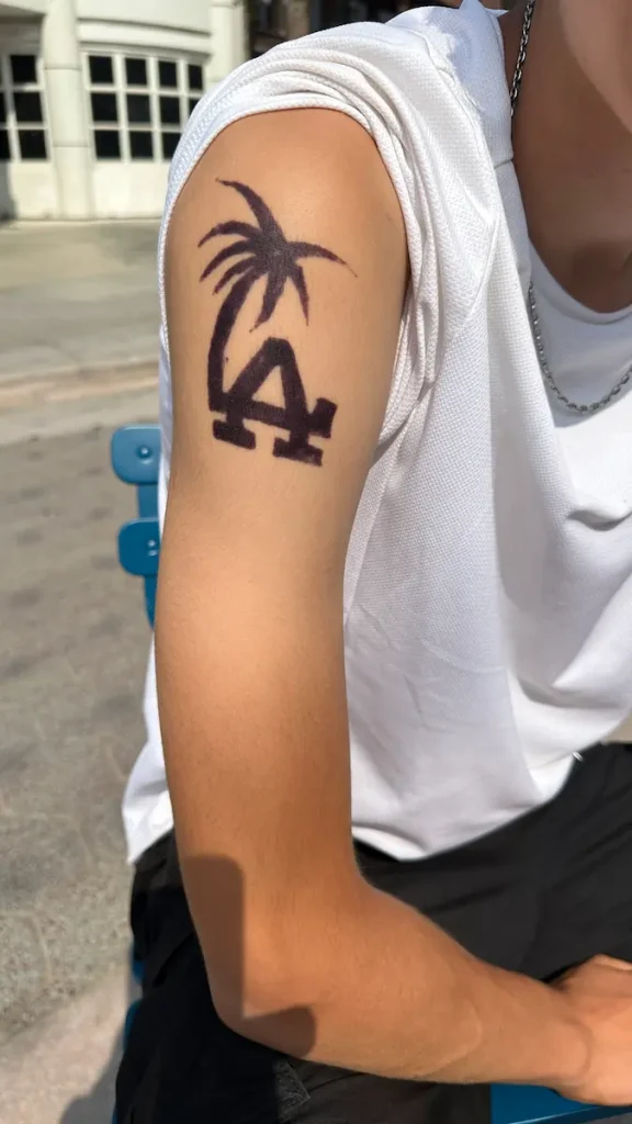 Photo du bras d'un adolescent, manche relevée, révélant un tatouage au henné, d'un palmier et des lettres LA, symbolisant la ville de Los Angeles.