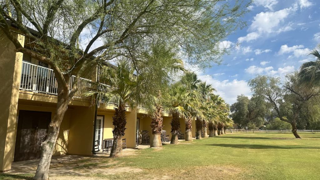 Photo de l'extérieur des bâtiments à The Ranch At Death Valley, Furnace Creek, montrant une rangée de palmiers devant les terrasses des chambres