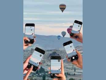 photo des mains de plusieurs personnes tenant leur téléphone portable et photographiant des montgolfières