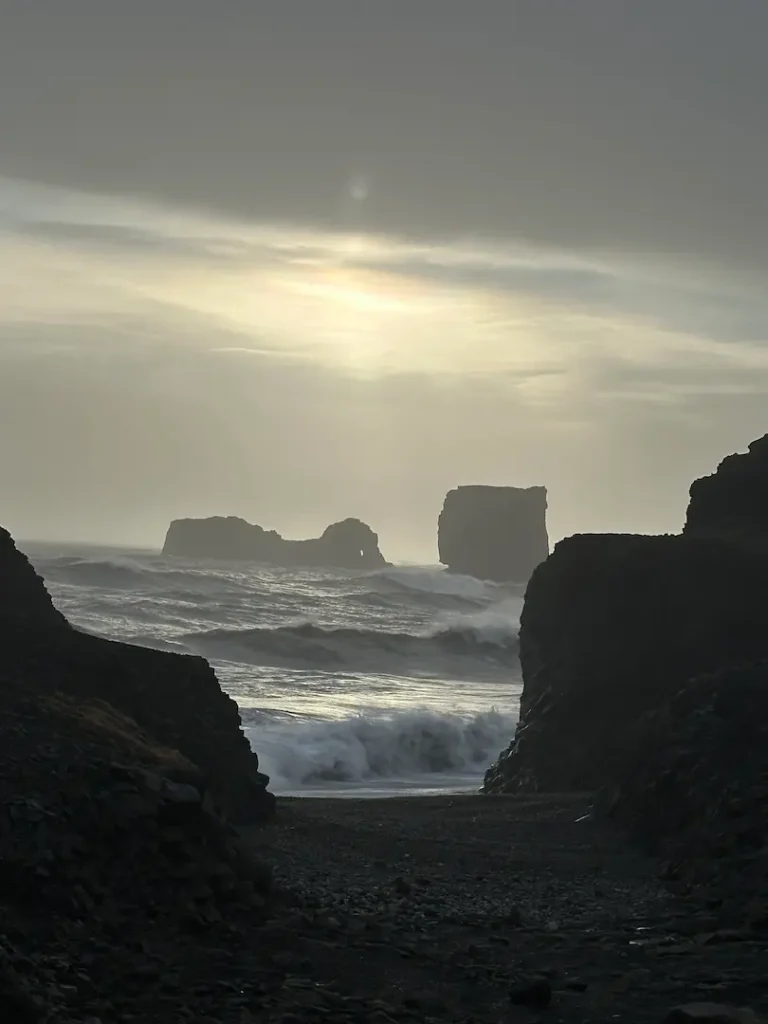 Photo prise au coucher du soleil depuis la péninsule de Dyrholaey montrant les formations rocheuses en pleine mer, en Islande