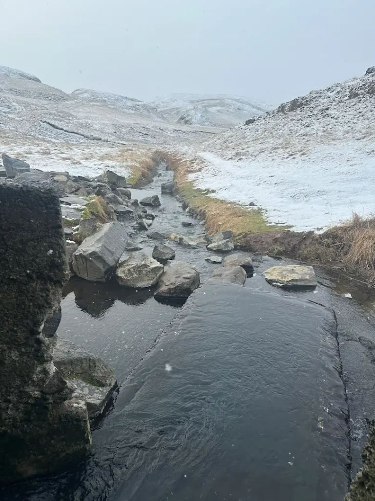 Bassin de la source chaude d'Hrunalaug avec le paysage enneigé en fond, Flúðir, Islande