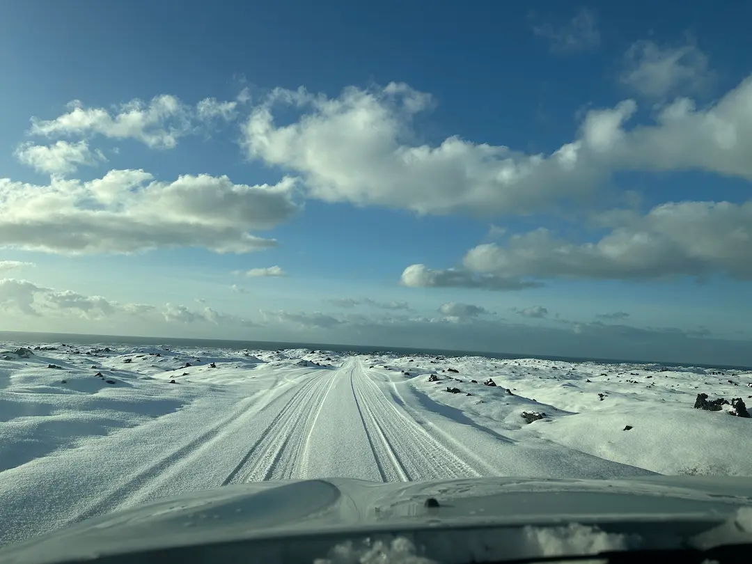 Photo d'une route enneigée, prise depuis l'intérieur d'une voiture, en Islande