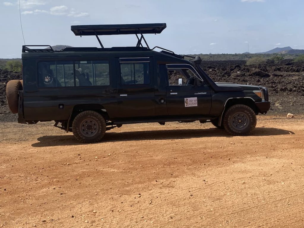 4x4 Land cruiser sur garé sur une piste de terre rouge avant la réserve de Taita Hills, Kenya