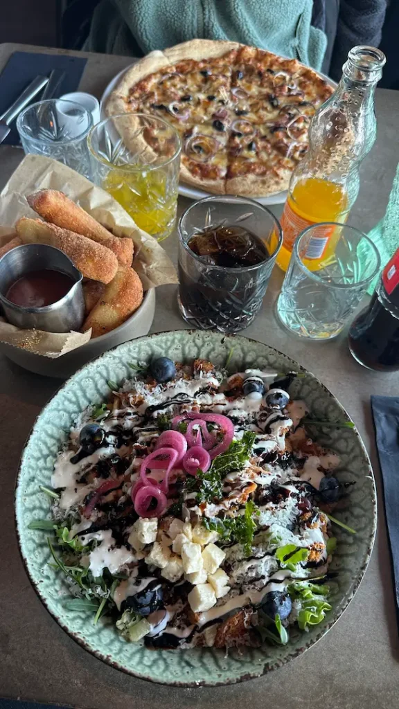 Table au restaurant avec une salade composé, une pizza et des boissons du repas d'une mère et son ado en Islande dans la péninsule de Snæfellsnes.