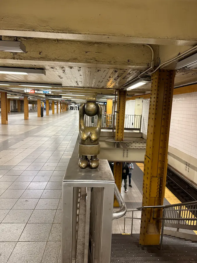 Photo d'un quai de métro de New York vide avec une statuette en bronze décorative devant les escalier