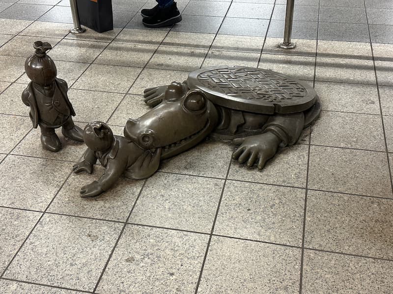 Statue de bronze dans le métro de New York montant un crocodile sortant d'une bouche d'égout