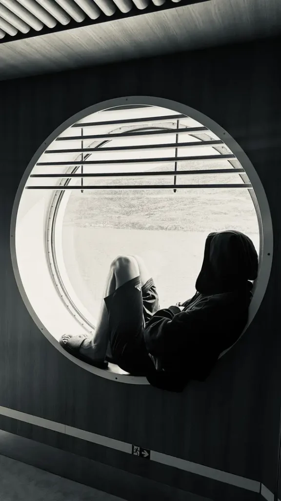 Ado assis dans un énorme hublot du ferry revenant de l'ile de Lewis vers le port d'Ullapool, Ecosse, Royaume Uni