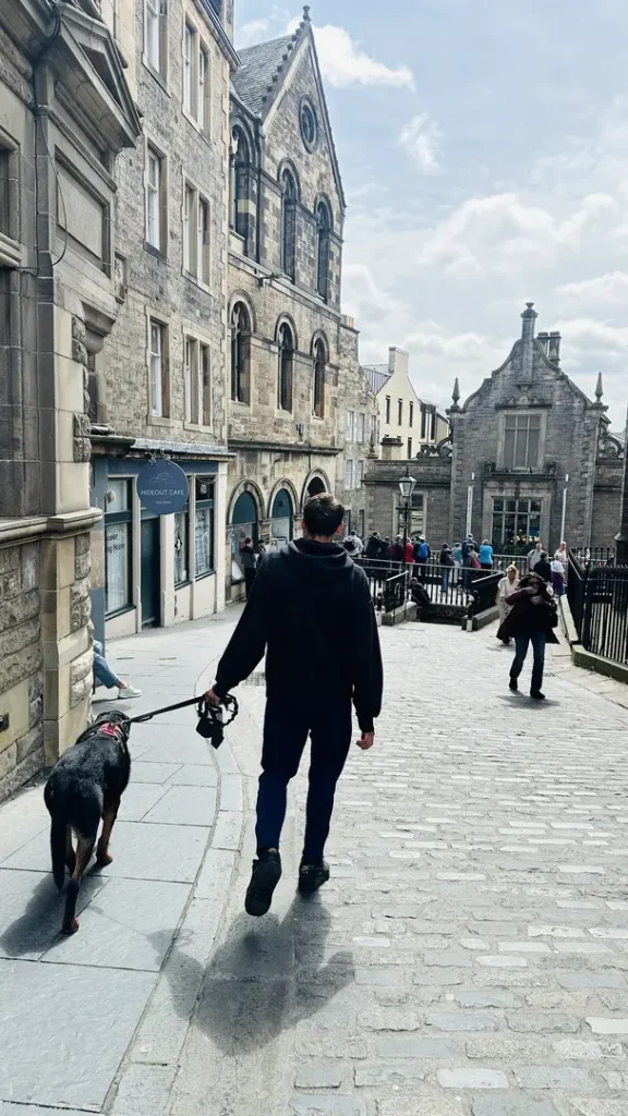 Un ado et son chien se promenant sur Victoria Street, Edimbourg, Ecosse, Royaume Uni