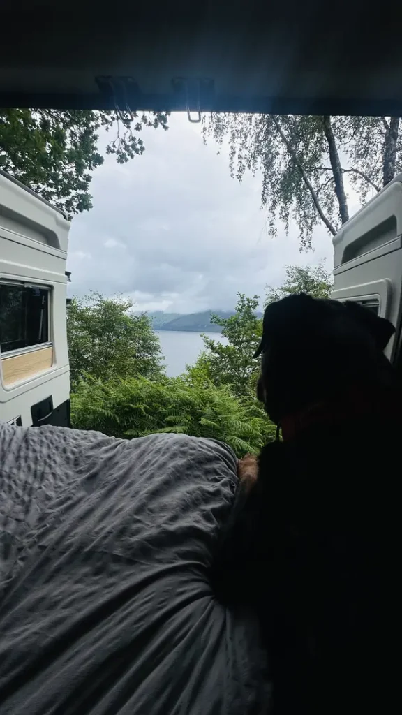 Portrait d'un chien sur le lit d'un van aménagé devant la porte arrière ouverte en Ecosse, Royaume Uni
