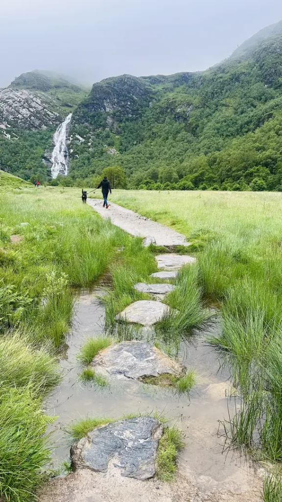 Ado et son chien marchant dans la vallée de la randonnée Steal Waterfall, Ecosse, Royaume Uni