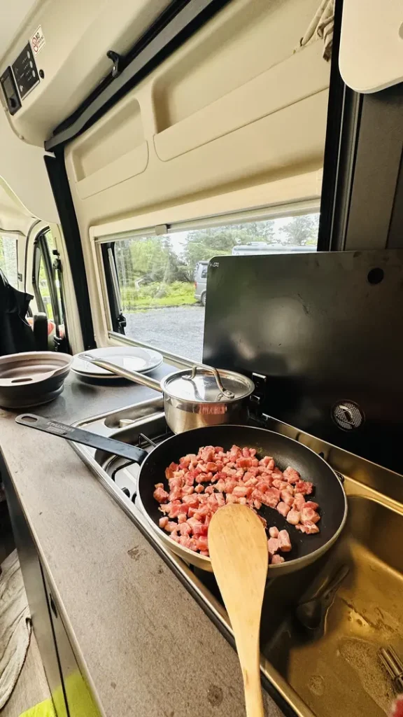 Une casserole et une poele sur le feu dans un van aménagé en Ecosse, Royaume Uni