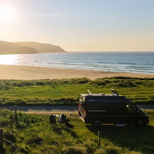 Adolescent et sa mère dans des chaises de camping, à côté d'un van aménagé, au coucher du soleil, devant Cliff beach, sur l'ile de Lewis dans les Hébrides extérieures, Ecosse, Royaume Uni